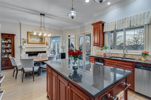 kitchen featuring hanging light fixtures, a sink, light wood-style floors, dishwasher, and backsplash