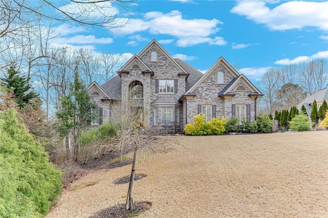 french country inspired facade featuring brick siding and stone siding