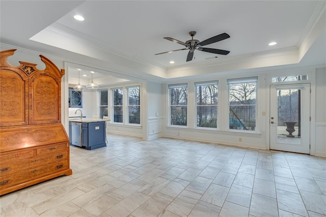 unfurnished living room featuring plenty of natural light, a ceiling fan, and a raised ceiling