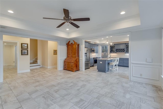 unfurnished living room featuring stairs, a ceiling fan, a tray ceiling, and recessed lighting