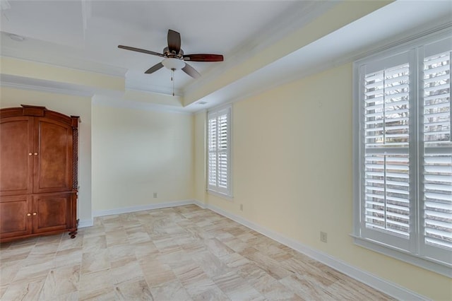 spare room featuring ornamental molding, a raised ceiling, ceiling fan, and a healthy amount of sunlight