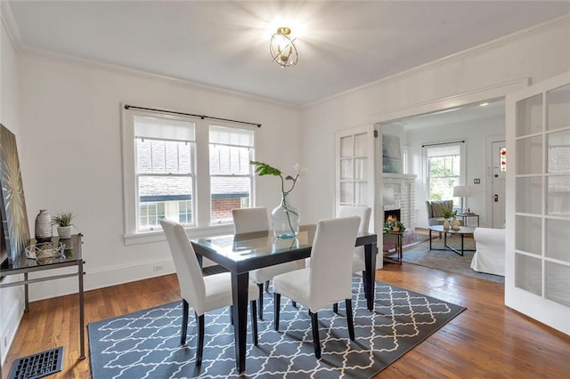 636 Cameron St SE, Atlanta, GA 30312 - dining area featuring wood finished floors, crown molding, a brick fireplace, and baseboards