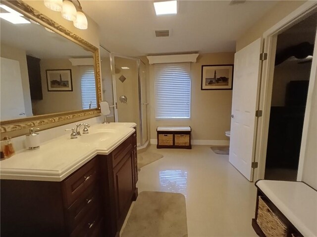 bathroom featuring toilet, vanity, and a shower with shower door