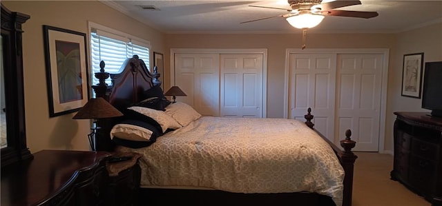 carpeted bedroom with multiple closets, ceiling fan, and crown molding