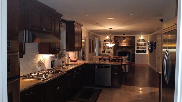 kitchen featuring dark brown cabinetry, sink, appliances with stainless steel finishes, a fireplace, and premium range hood