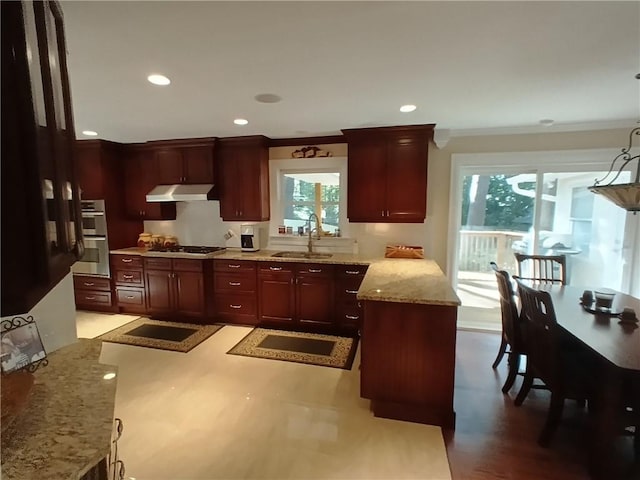 kitchen with ornamental molding, appliances with stainless steel finishes, light stone countertops, pendant lighting, and sink