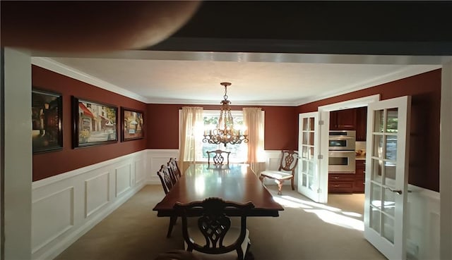 carpeted dining area featuring ornamental molding, french doors, and a notable chandelier