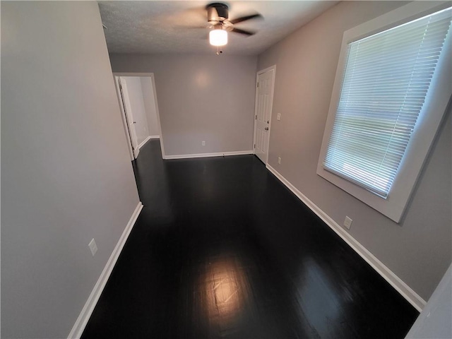 empty room with ceiling fan and dark hardwood / wood-style floors