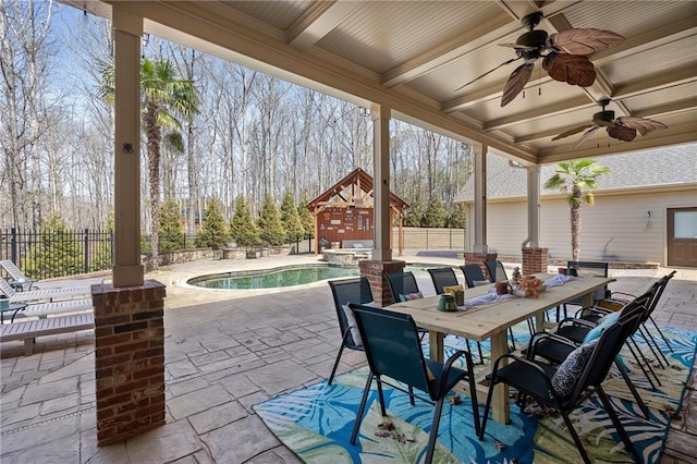 view of patio / terrace featuring a pool with connected hot tub, outdoor dining space, a ceiling fan, and fence