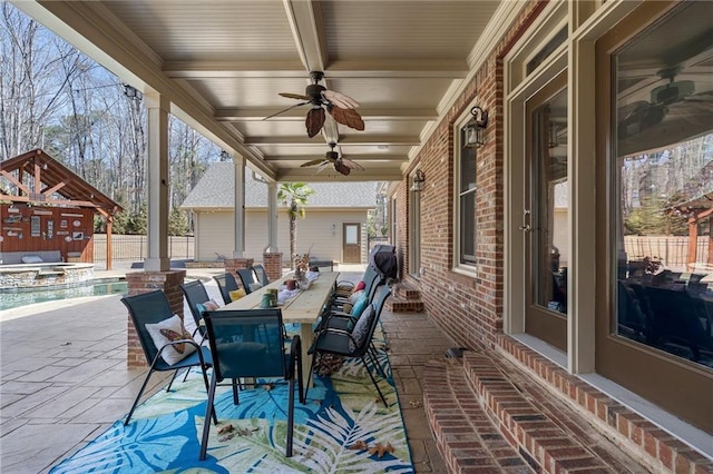 view of patio with outdoor dining space, a ceiling fan, fence, and a pool with connected hot tub