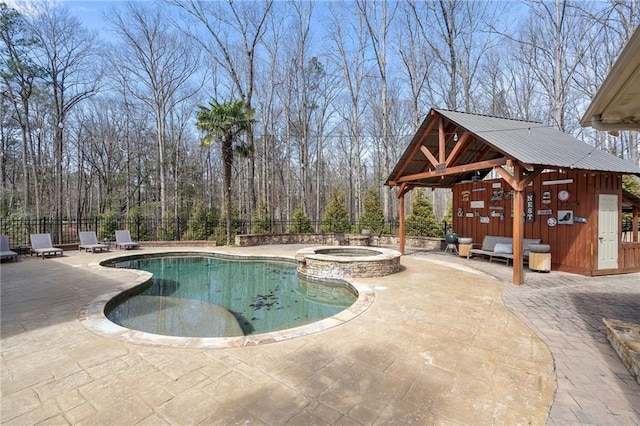 view of swimming pool with a patio, an outbuilding, a pool with connected hot tub, and fence