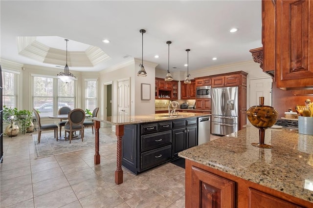 kitchen featuring a breakfast bar area, light stone counters, a center island with sink, appliances with stainless steel finishes, and a raised ceiling