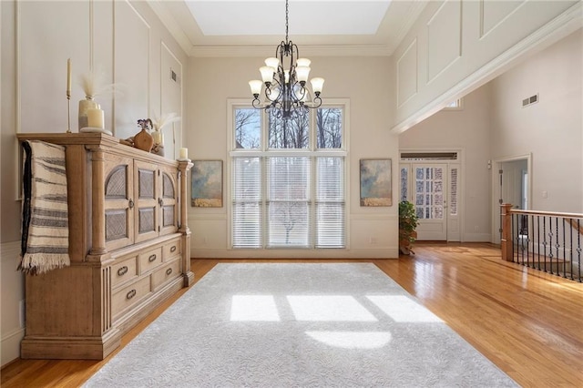 interior space with visible vents, crown molding, an inviting chandelier, and wood finished floors