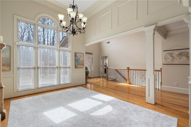 interior space with wood finished floors, visible vents, a high ceiling, crown molding, and a chandelier