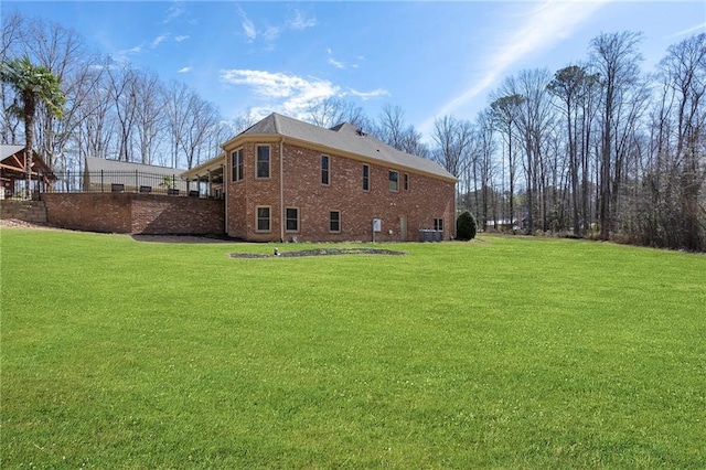 rear view of house featuring cooling unit, a lawn, and brick siding