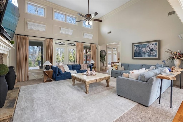 living area with visible vents, ceiling fan, a towering ceiling, and ornamental molding