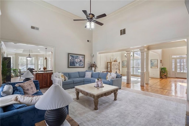 living area featuring a wealth of natural light, visible vents, crown molding, and ornate columns