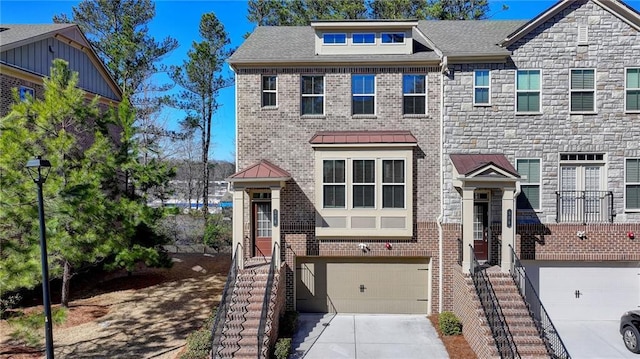 townhome / multi-family property featuring a garage, brick siding, concrete driveway, stone siding, and a standing seam roof