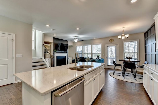 kitchen with dark wood-style flooring, a fireplace, a sink, white cabinetry, and stainless steel dishwasher