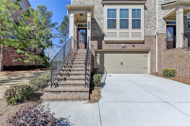 view of exterior entry featuring brick siding, driveway, and an attached garage