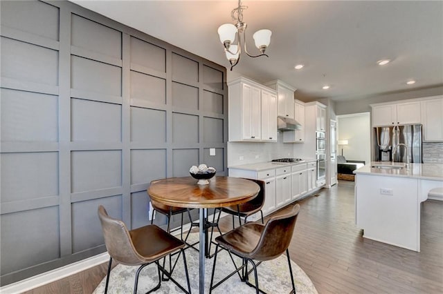 kitchen featuring light countertops, a decorative wall, decorative backsplash, appliances with stainless steel finishes, and under cabinet range hood