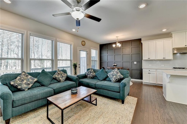 living room featuring ceiling fan with notable chandelier, dark wood-style flooring, and recessed lighting