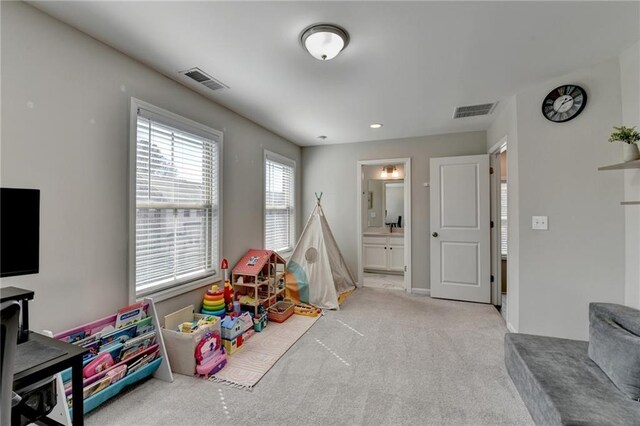 recreation room featuring light carpet, baseboards, and visible vents