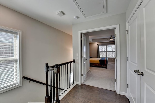 hallway featuring attic access, baseboards, dark wood-style flooring, and an upstairs landing