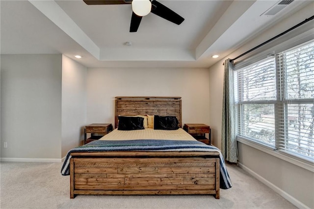 carpeted bedroom with visible vents, baseboards, a raised ceiling, and recessed lighting