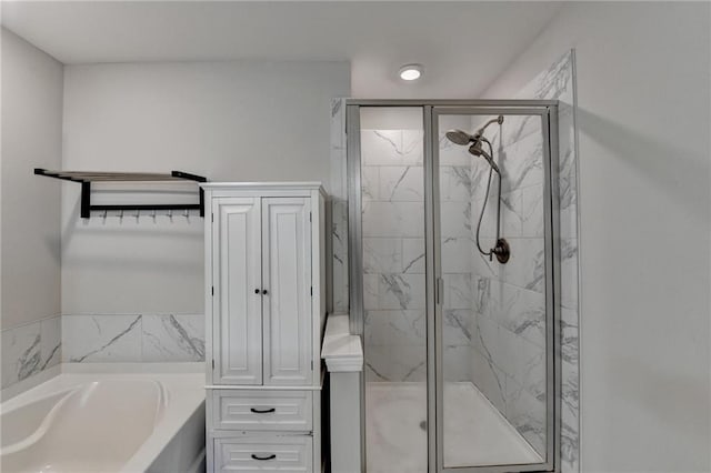 full bathroom featuring a garden tub and a marble finish shower