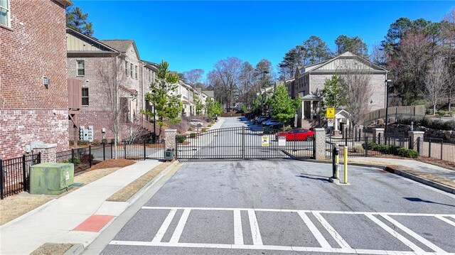 view of road featuring a residential view, a gated entry, curbs, a gate, and sidewalks