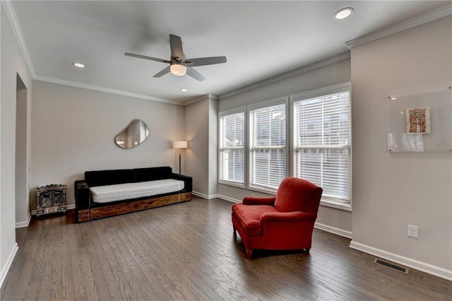 sitting room with wood-type flooring, crown molding, visible vents, and baseboards