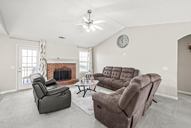 living room featuring arched walkways, a fireplace, lofted ceiling, visible vents, and light carpet