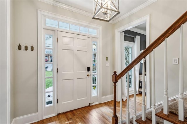 foyer with a notable chandelier, ornamental molding, and light wood-type flooring