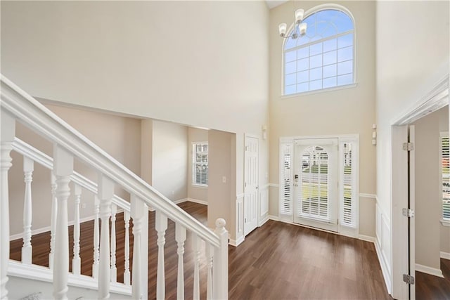 foyer featuring a towering ceiling, an inviting chandelier, and dark wood-type flooring