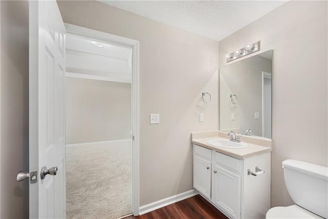 bathroom with a textured ceiling, vanity, toilet, and hardwood / wood-style flooring