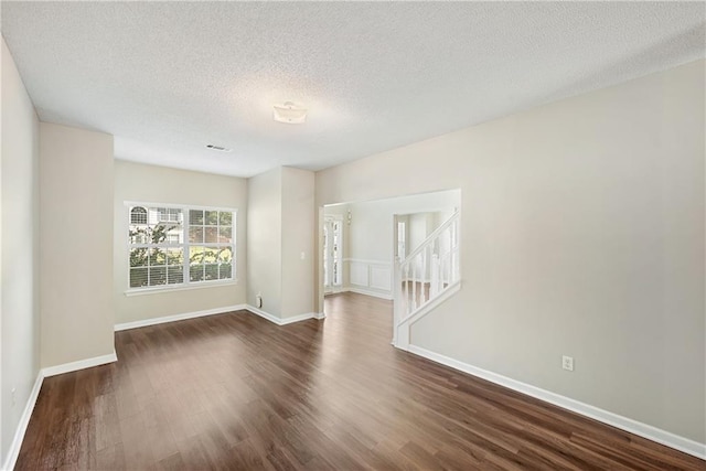 unfurnished room featuring a textured ceiling and dark hardwood / wood-style flooring