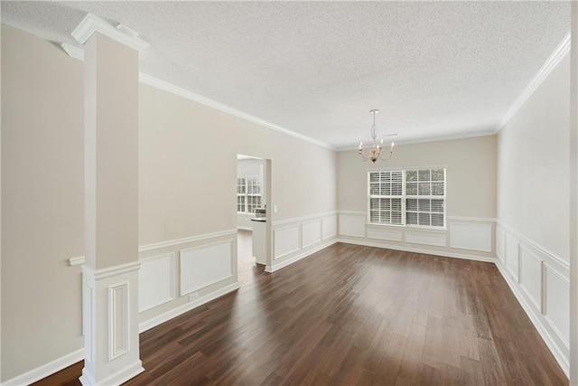 spare room with an inviting chandelier, a textured ceiling, ornamental molding, and dark hardwood / wood-style floors