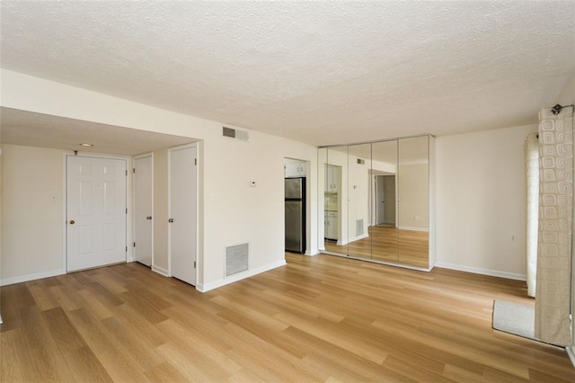 empty room with light hardwood / wood-style floors and a textured ceiling