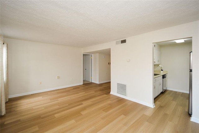 spare room with light hardwood / wood-style flooring and a textured ceiling