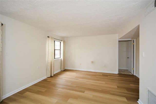 unfurnished room with a textured ceiling and light hardwood / wood-style flooring