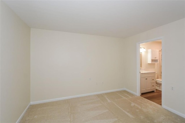 unfurnished bedroom featuring light carpet and ensuite bath