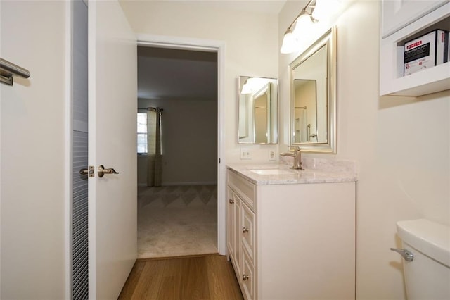 bathroom featuring vanity, wood-type flooring, and toilet