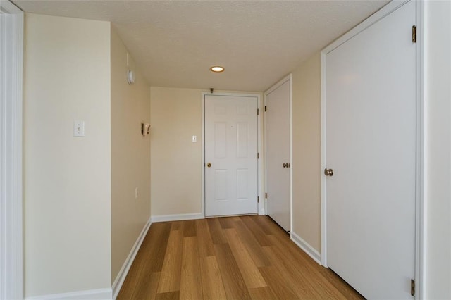 corridor featuring light hardwood / wood-style floors and a textured ceiling