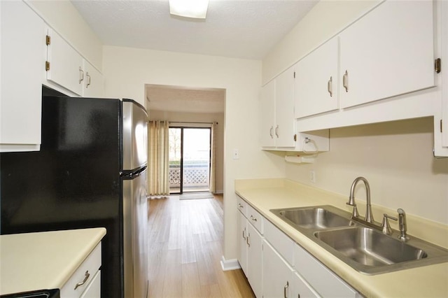 kitchen with white cabinetry, sink, stainless steel refrigerator, and light wood-type flooring