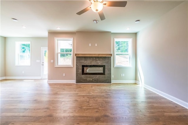 unfurnished living room with plenty of natural light, a high end fireplace, and hardwood / wood-style floors