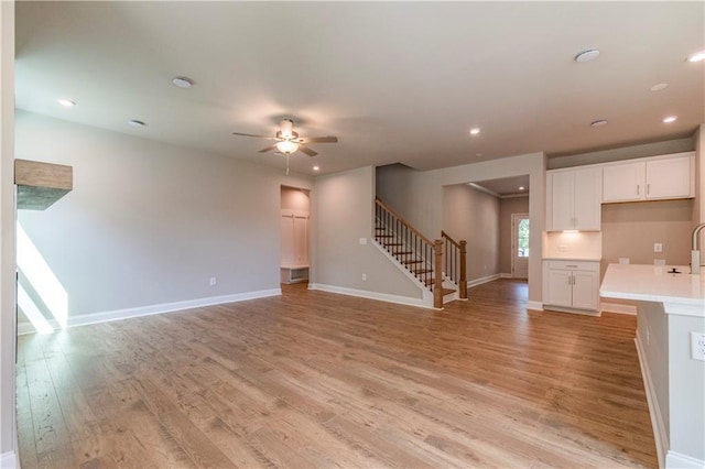 unfurnished living room featuring light hardwood / wood-style floors, ceiling fan, and sink