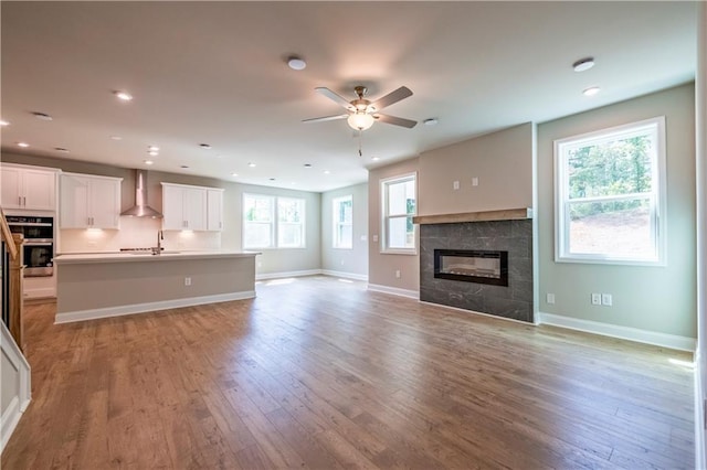 unfurnished living room featuring a tile fireplace, sink, plenty of natural light, and light hardwood / wood-style flooring