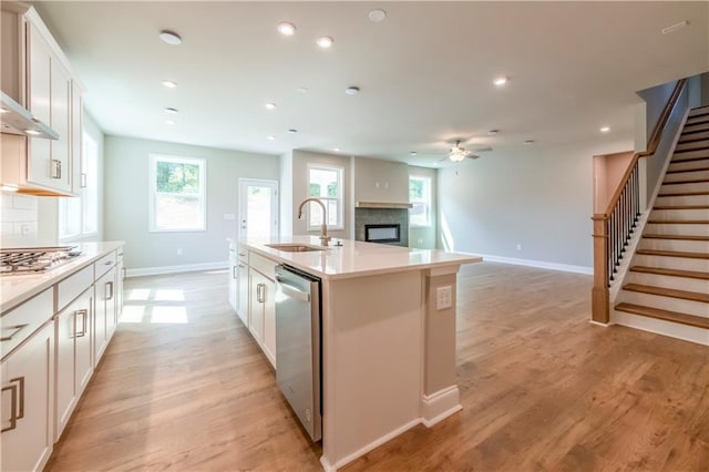 kitchen with decorative backsplash, appliances with stainless steel finishes, sink, white cabinetry, and an island with sink