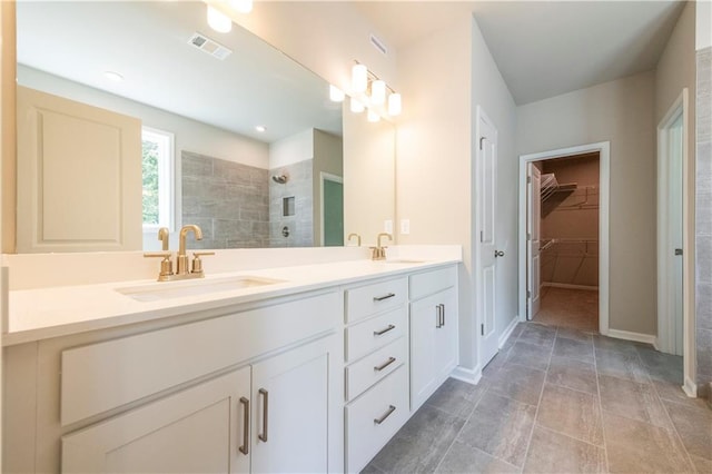 bathroom with a tile shower and vanity